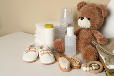 Baby clothes, toy bear and accessories on white table