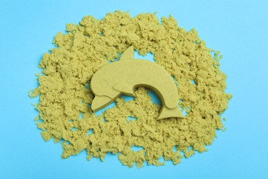 Yellow kinetic sand on light blue background, flat lay