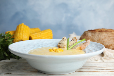 Photo of Delicious corn cream soup served on white wooden table