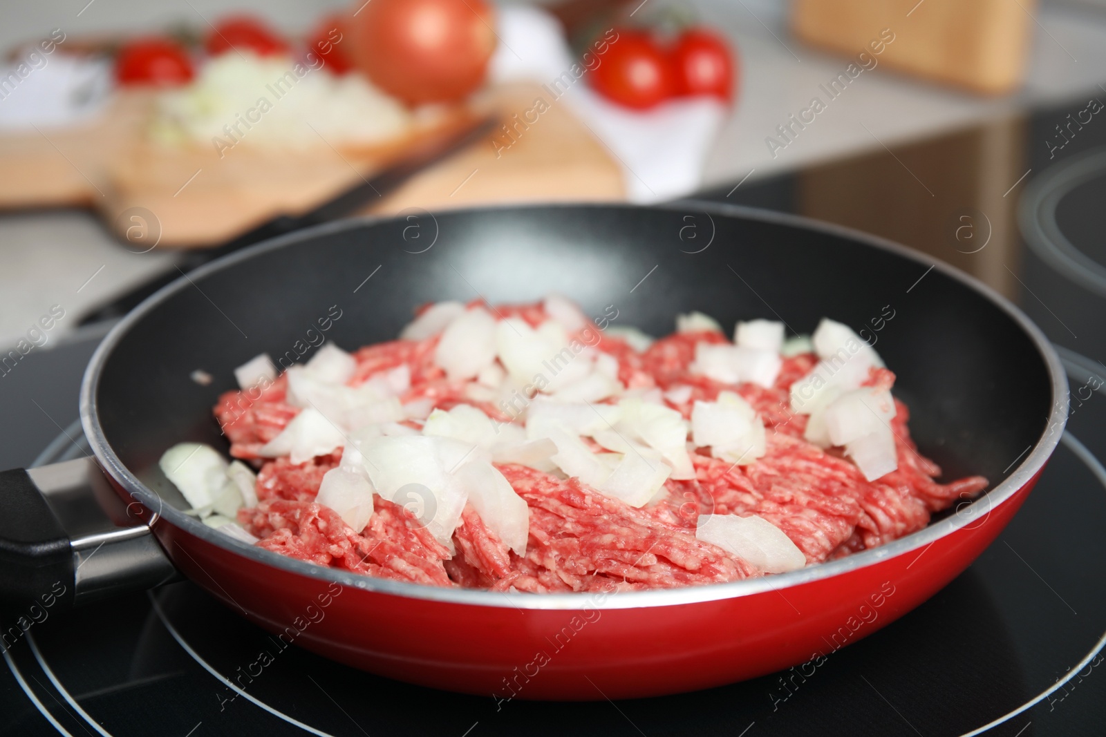 Photo of Frying pan with raw minced meat and chopped onion on induction stove, closeup