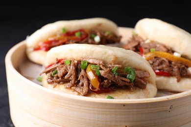 Photo of Delicious gua bao in bamboo steamer on table, closeup
