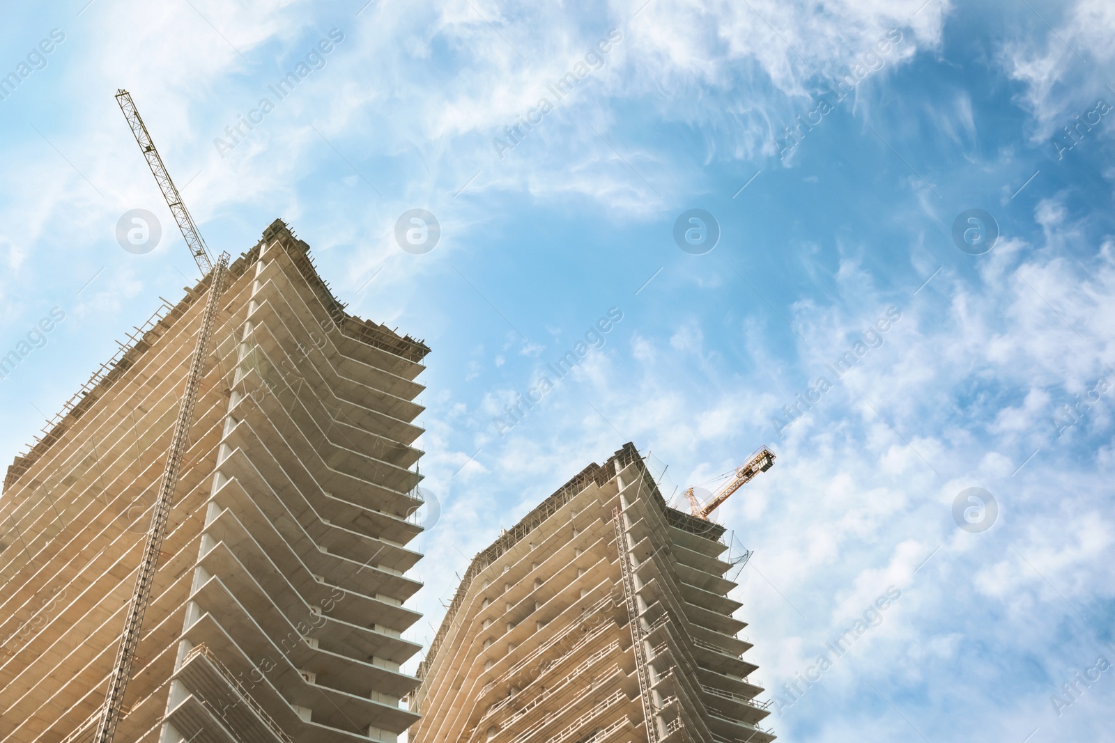 Photo of Construction site with tower cranes near unfinished buildings, low angle view