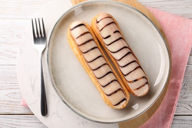 Photo of Tasty glazed eclairs served on wooden rustic table, top view