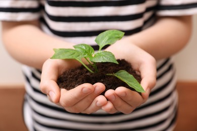 Photo of Woman holding soil with green seedling, closeup