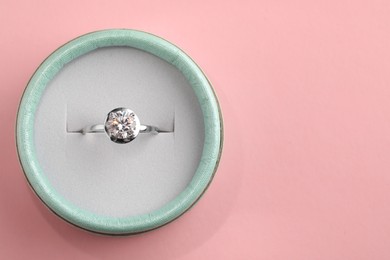 Photo of Beautiful box with engagement ring on pink background, top view. Space for text