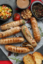 Tasty fresh grilled sausages with vegetables on grey table, flat lay