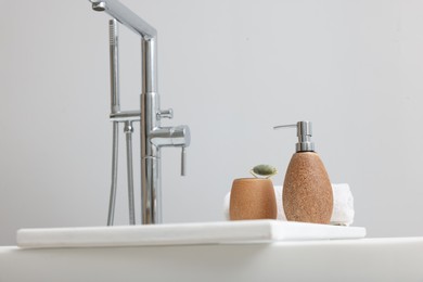 Photo of Different personal care products and accessories on bath tub in bathroom, space for text