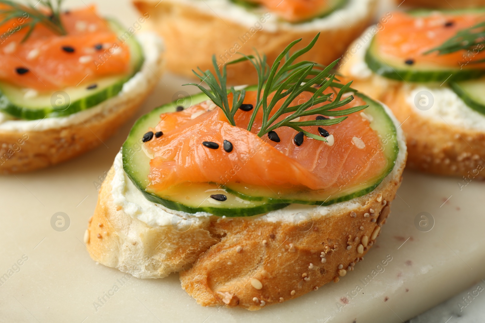 Photo of Tasty canapes with salmon, cucumber and cream cheese on table, closeup