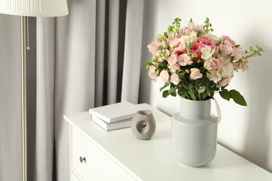 Photo of Beautiful bouquet of fresh flowers in vase on chest of drawers indoors