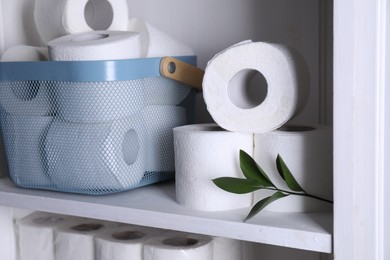 Photo of Toilet paper rolls and green leaves on white shelf