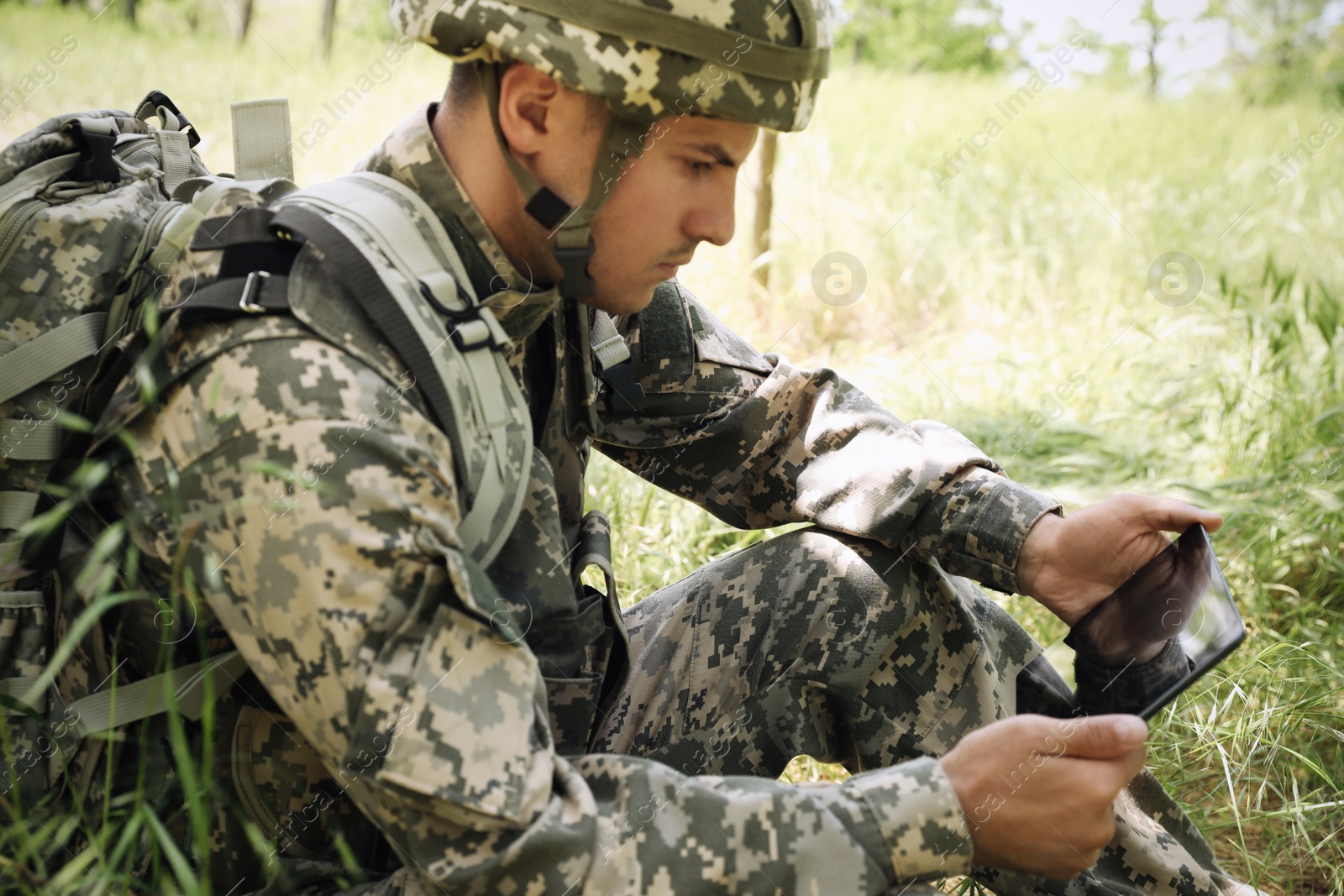 Photo of Soldier with backpack using tablet in forest