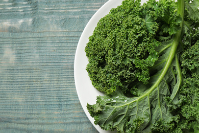 Photo of Fresh kale leaves on light blue wooden table, top view. Space for text