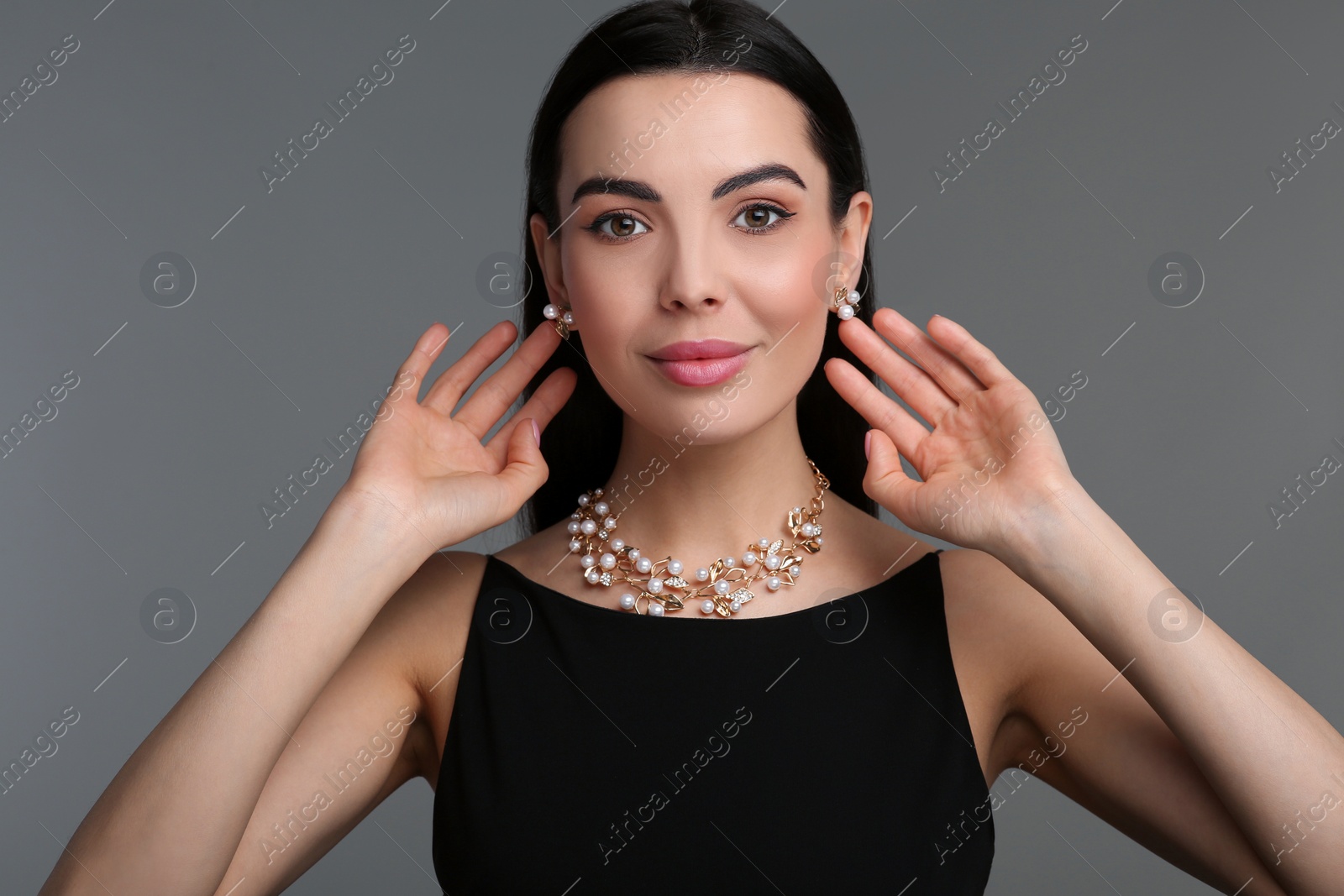 Photo of Beautiful young woman with elegant jewelry on dark grey background