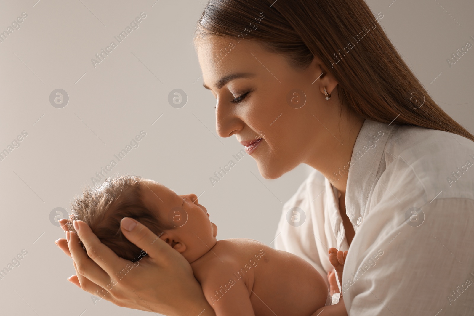 Photo of Mother holding her newborn baby on light grey background