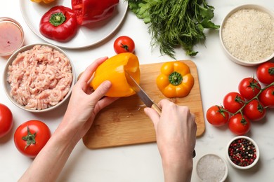 Woman making stuffed peppers with ground meat at white table, top view