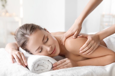 Photo of Young woman enjoying massage in spa salon