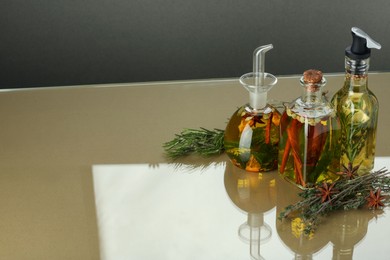 Photo of Cooking oil with different spices and herbs in bottles on colorful table, above view. Space for text