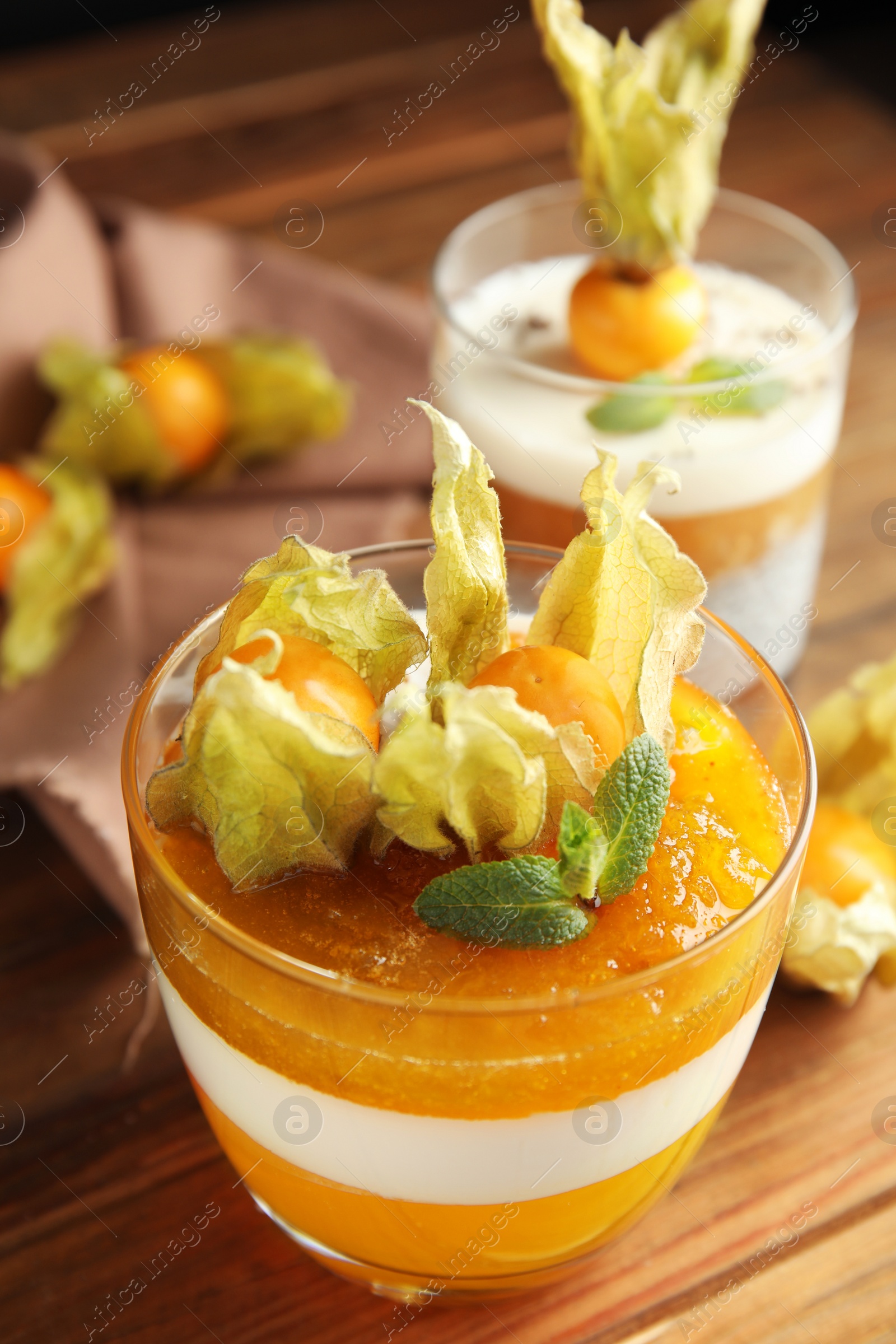 Photo of Delicious dessert decorated with physalis on wooden table, closeup