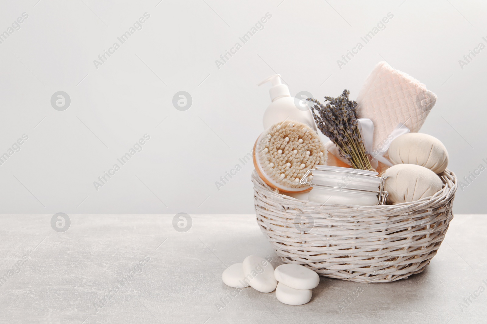 Photo of Spa gift set of different luxury products in wicker basket on grey table, space for text