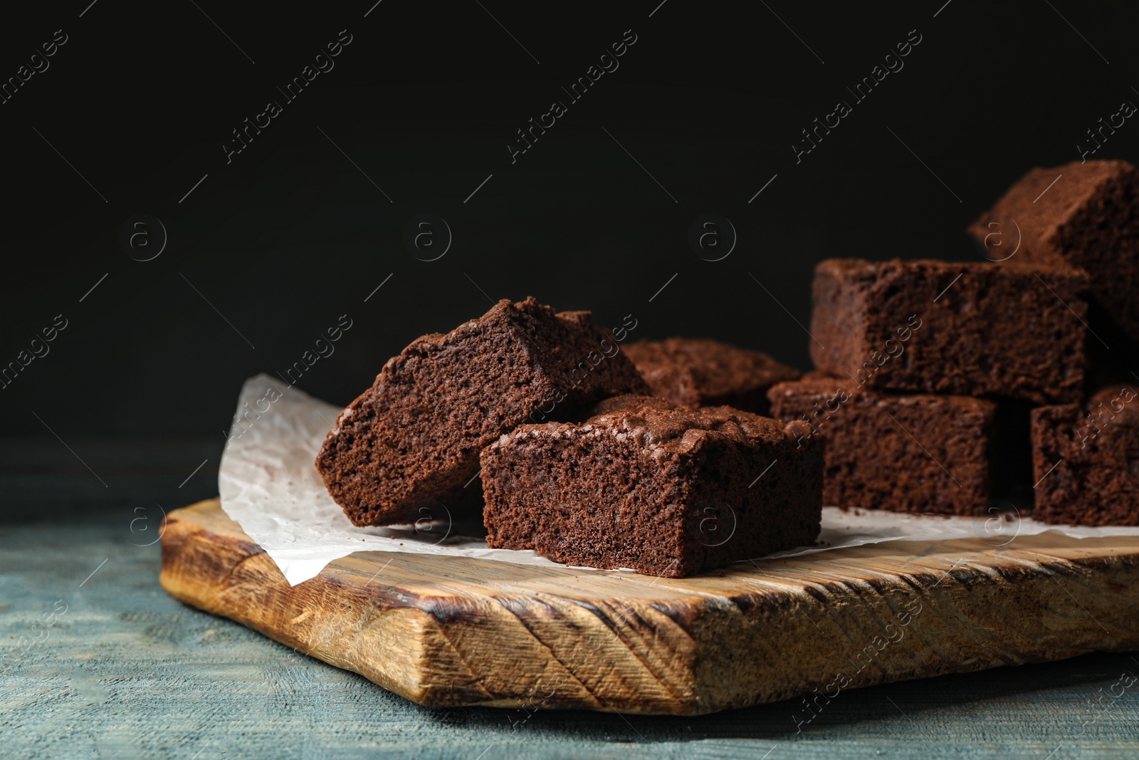 Photo of Wooden board with fresh brownies on table. Delicious chocolate pie