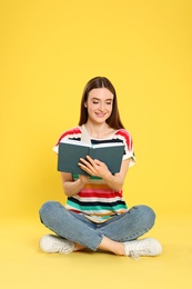 Young woman reading book on color background, space for text