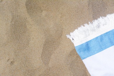 Photo of White and light blue striped towel on sandy beach, top view. Space for text