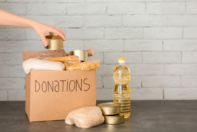 Female volunteer putting food into donation box on table