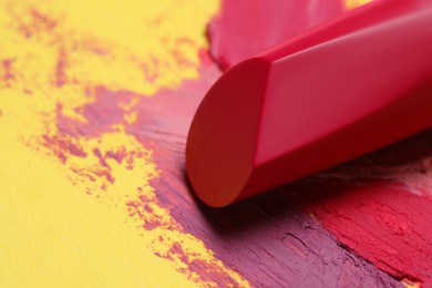 Bright lipstick and different smears on yellow background, closeup