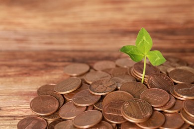 Photo of Pile of coins with green sprout on wooden table, closeup. Investment concept