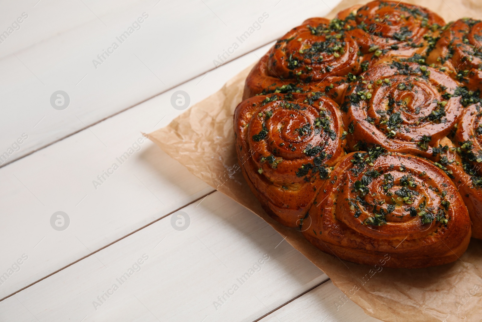 Photo of Traditional pampushka rolls with garlic and herbs on white wooden table. Space for text