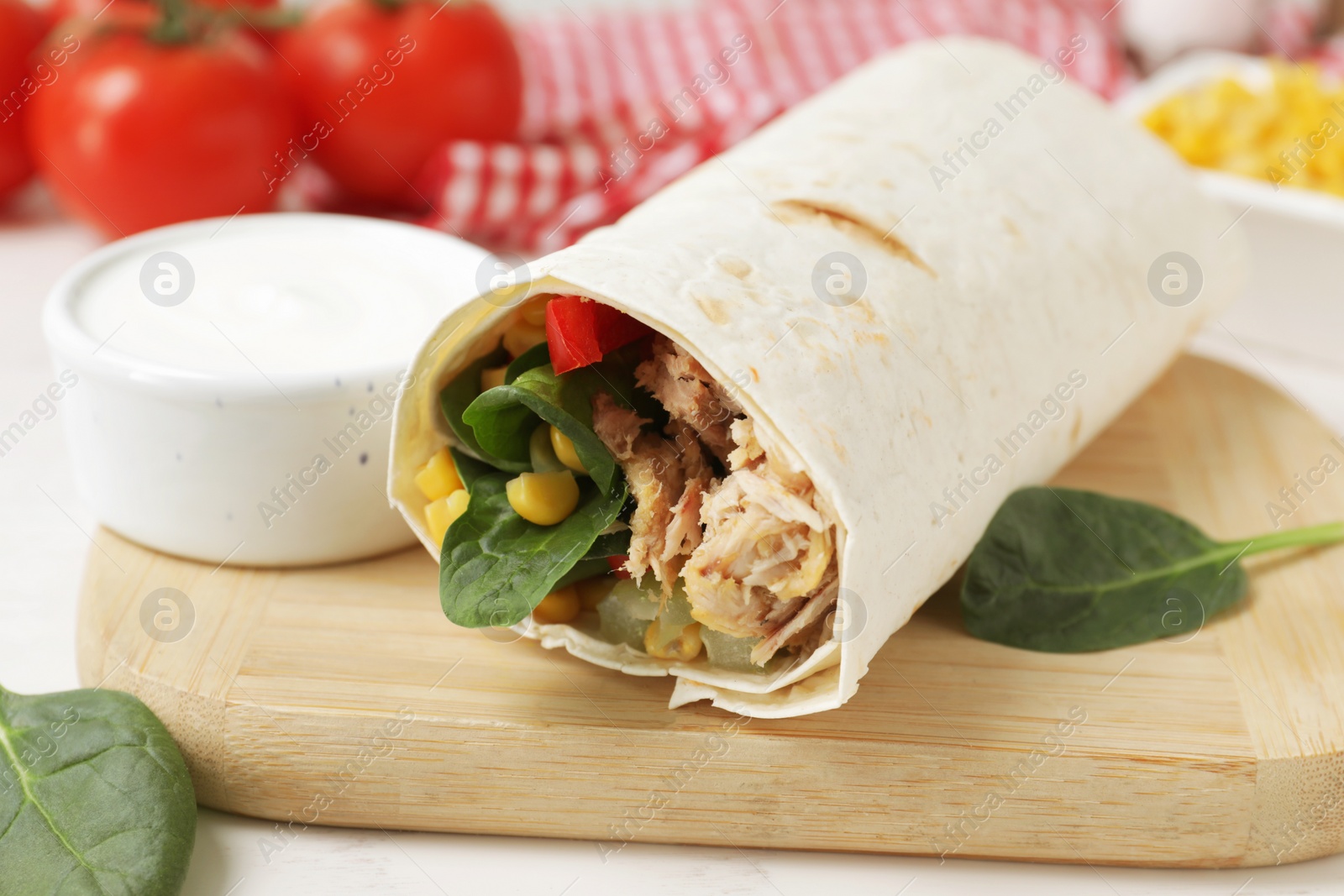 Photo of Delicious tortilla wrap with tuna on white wooden table, closeup