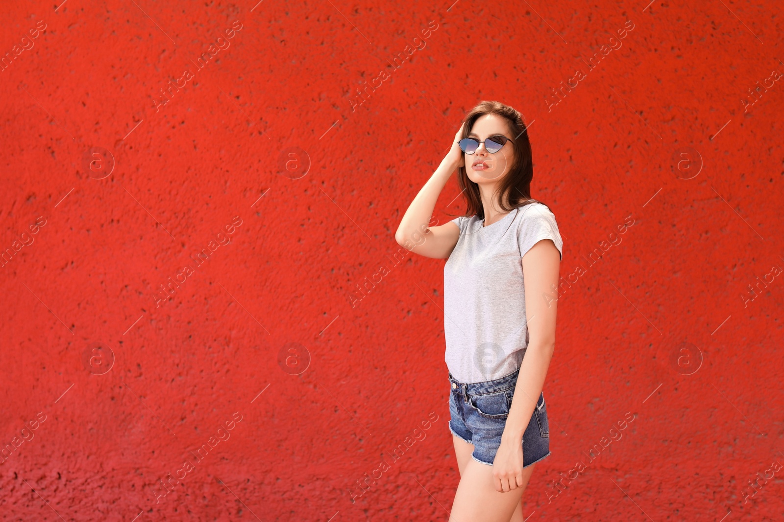 Photo of Young woman wearing gray t-shirt near color wall on street