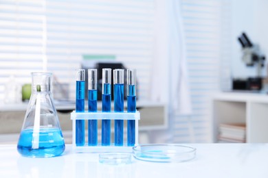 Photo of Laboratory analysis. Different glassware with blue liquid on white table indoors