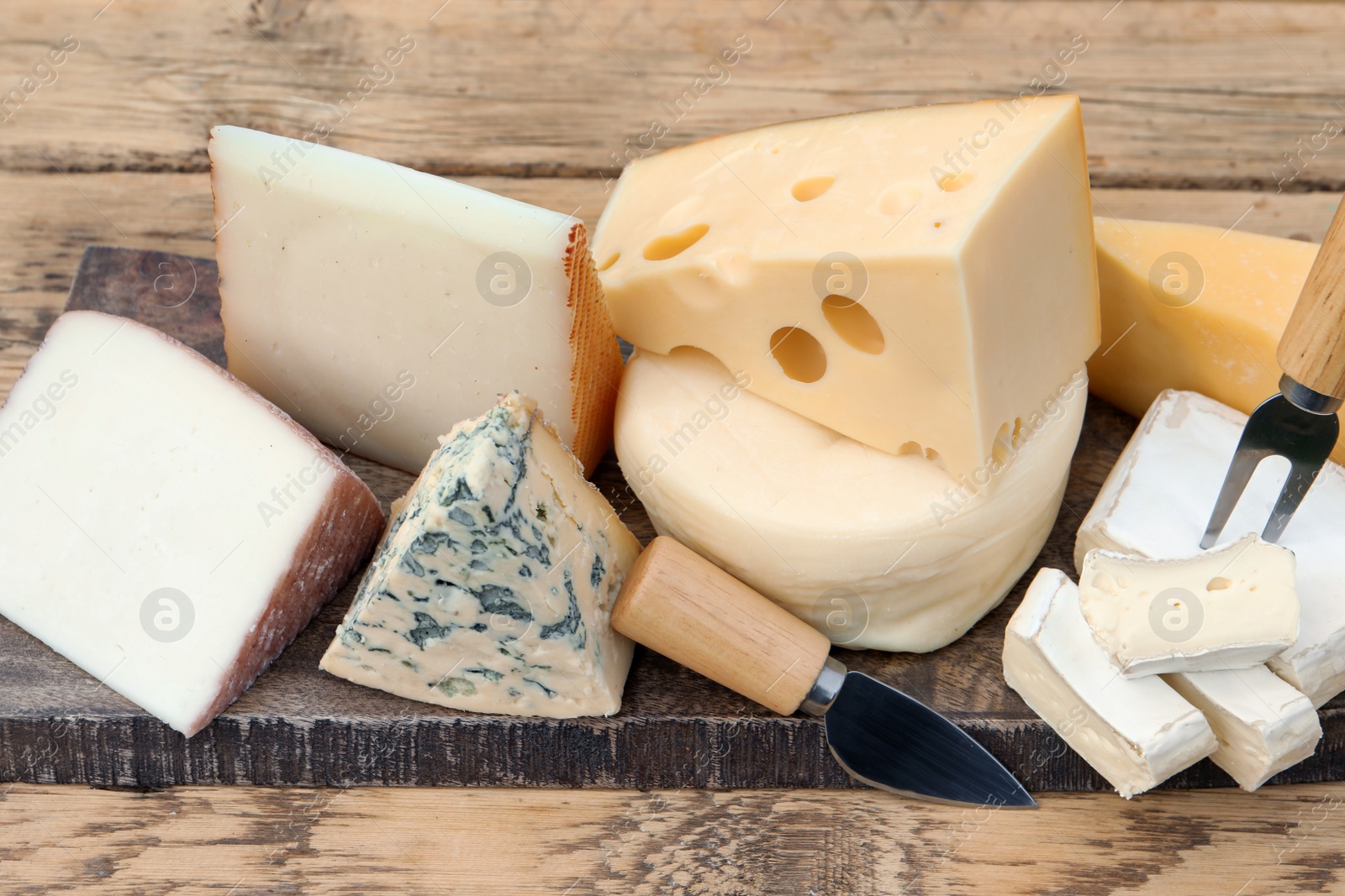 Photo of Different types of delicious cheeses on wooden table