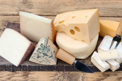 Different types of delicious cheeses on wooden table