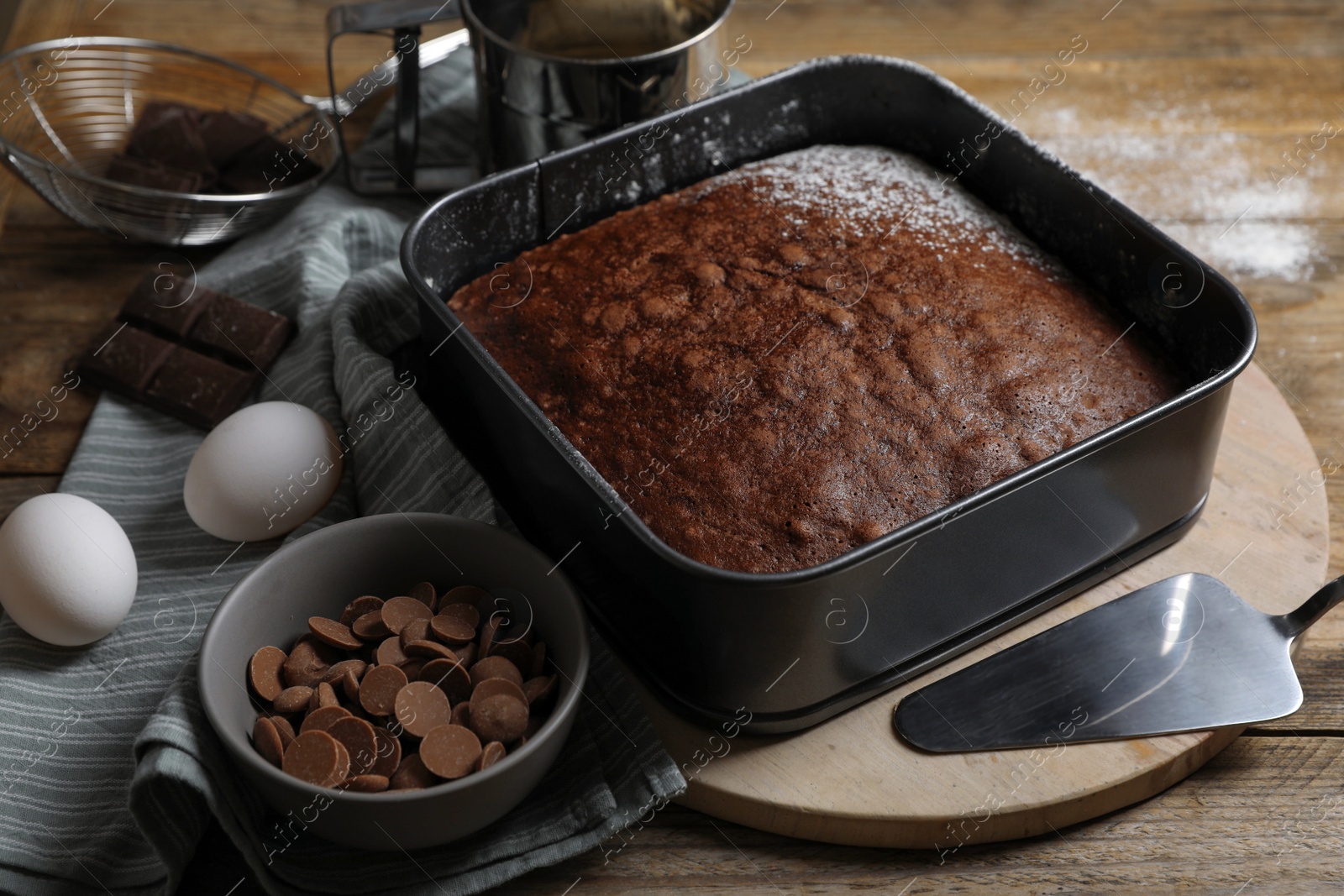 Photo of Homemade chocolate sponge cake and ingredients on wooden table