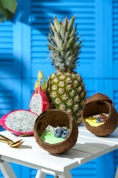 Photo of Tasty smoothie bowl served in coconut shells on white wooden table