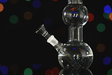 Photo of Closeup view of glass bong against blurred lights. Smoking device