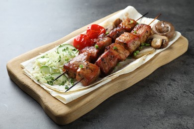 Delicious shish kebabs with vegetables and lavash on grey table