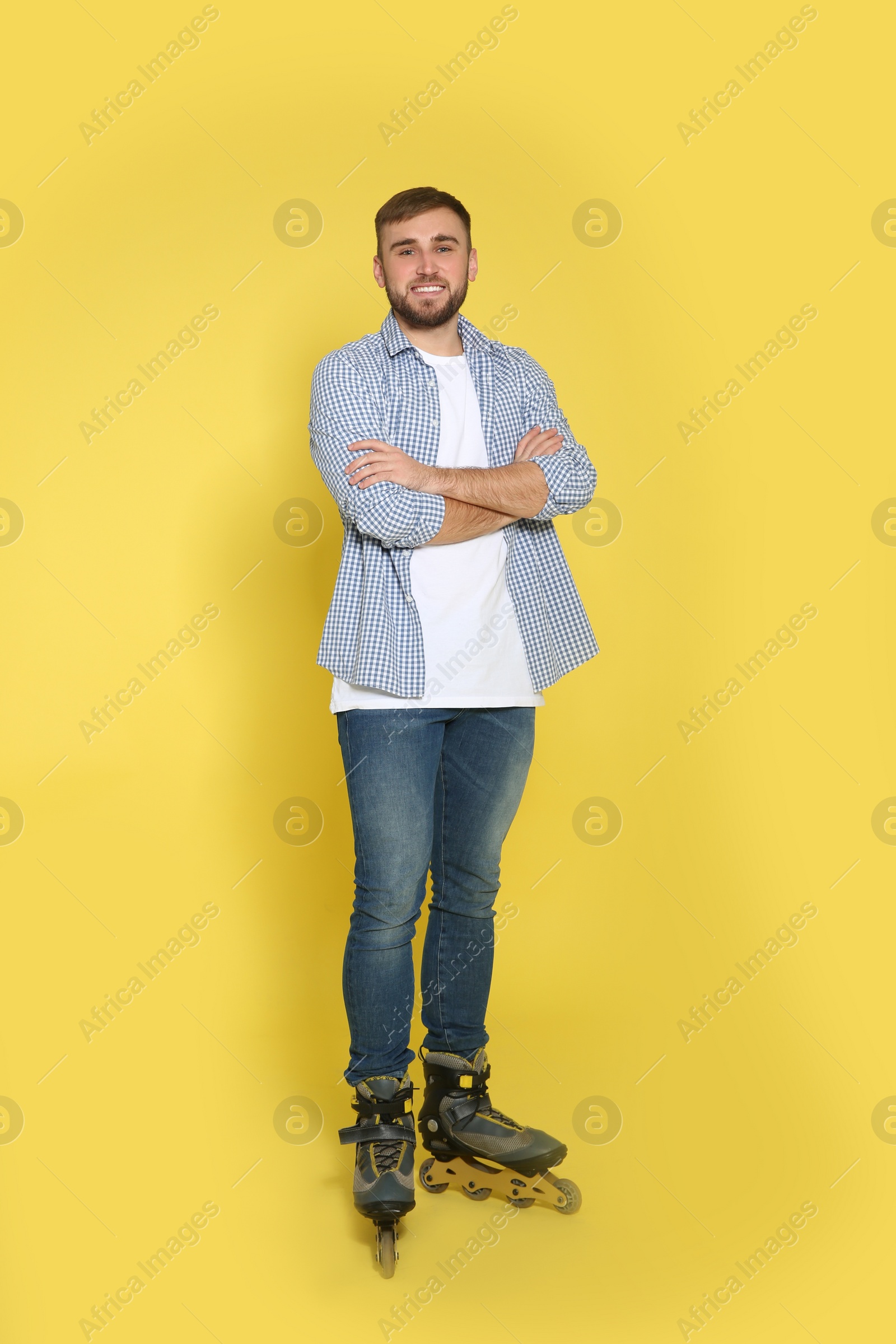 Photo of Full length portrait of young man with inline roller skates on color background