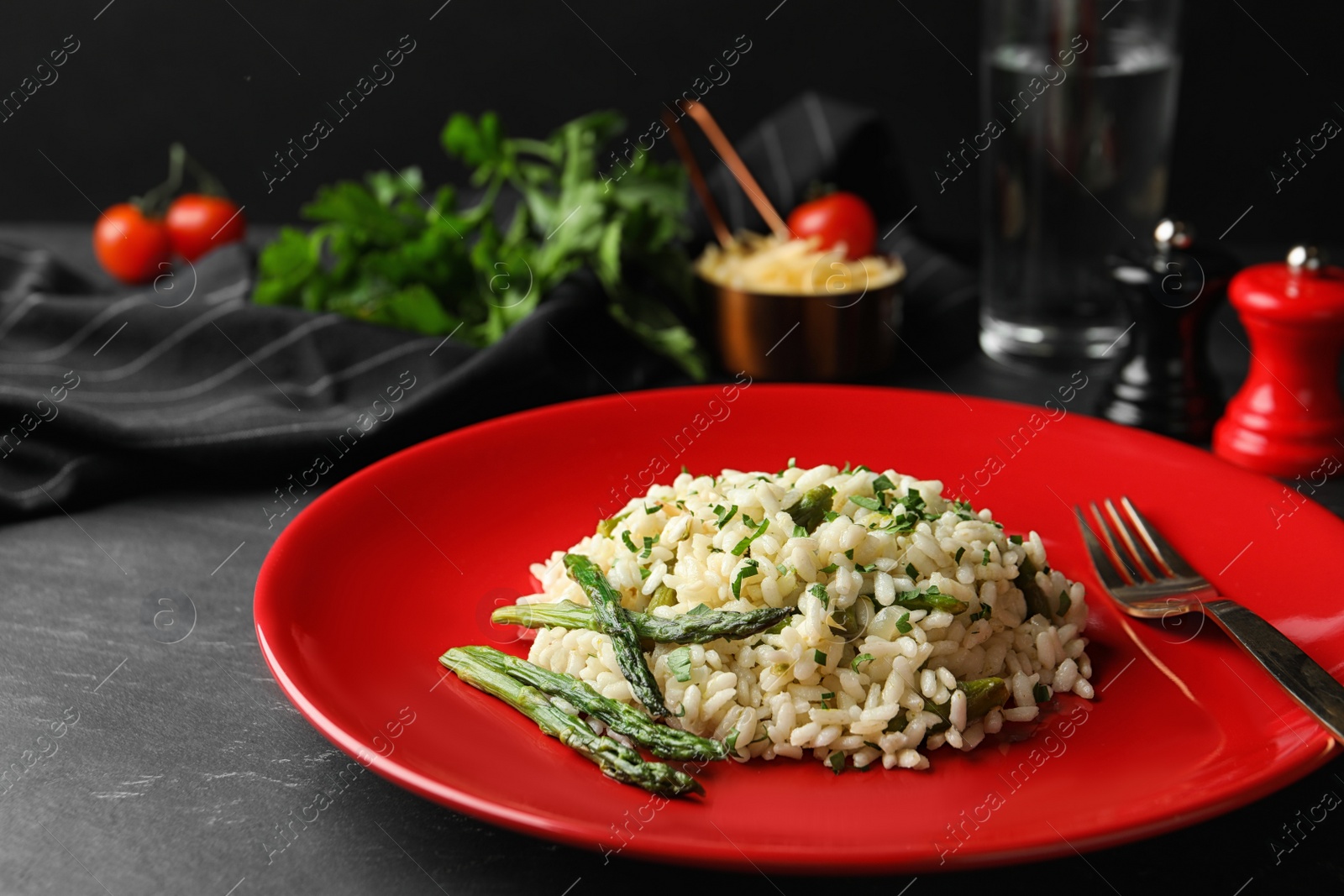 Photo of Delicious risotto with asparagus served on grey table
