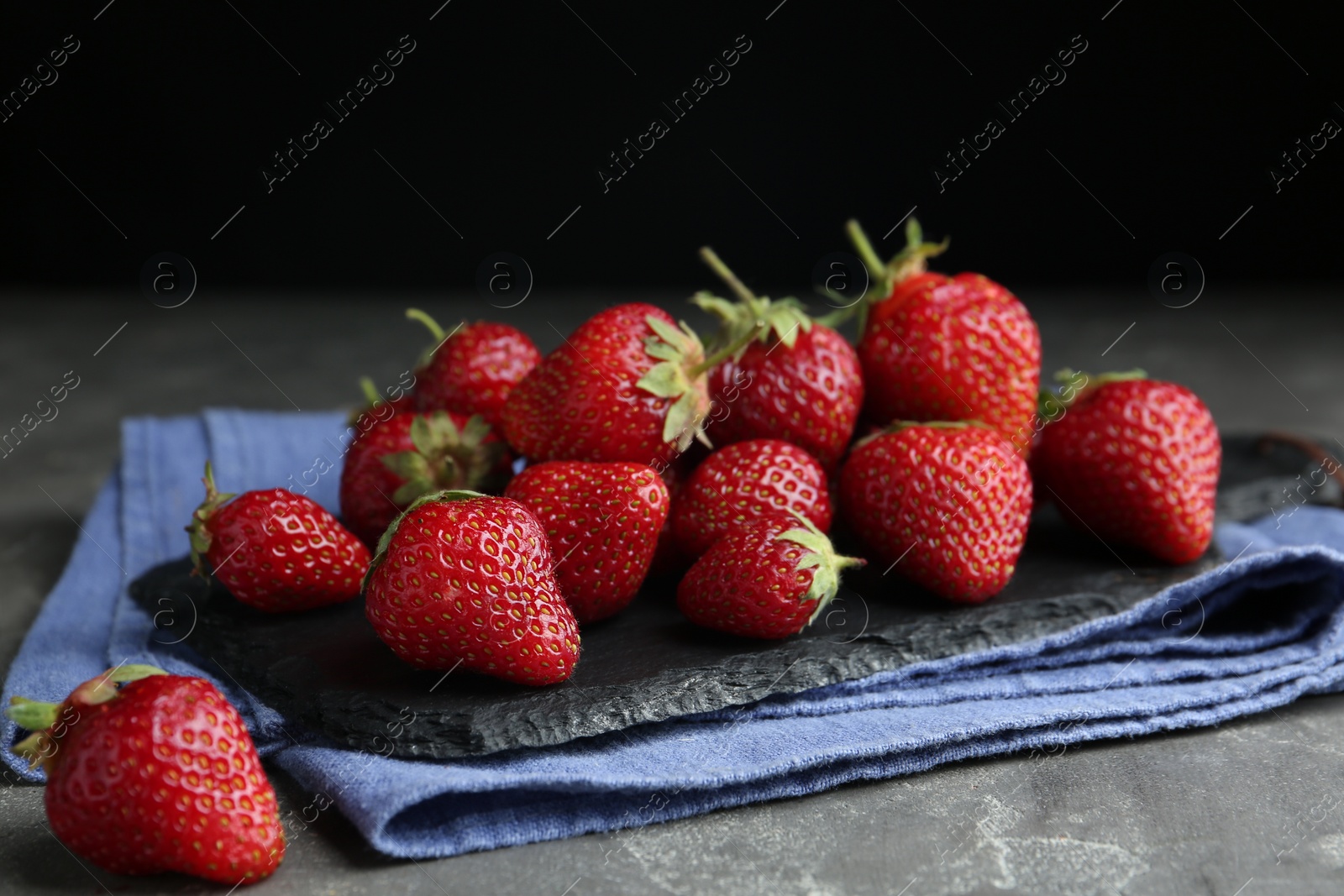 Photo of Many delicious ripe strawberries on grey table