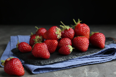 Many delicious ripe strawberries on grey table