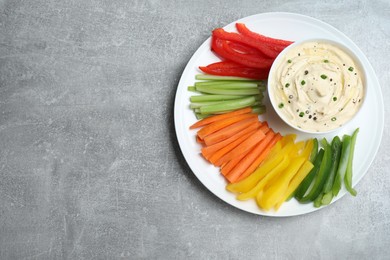 Photo of Fresh raw vegetable sticks and sauce on grey table, top view. Space for text