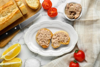 Photo of Tasty sandwiches with cod liver on white marble table, flat lay