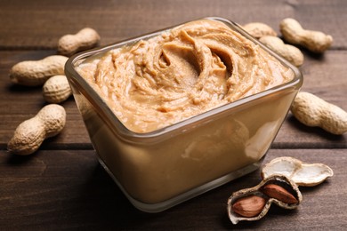 Photo of Yummy peanut butter in glass bowl on wooden table, closeup