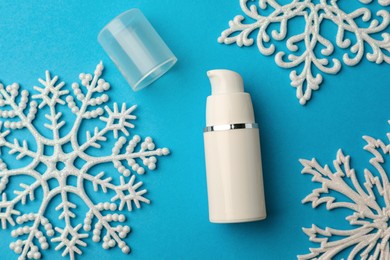 Photo of Hand cream and snowflakes on light blue background, flat lay. Winter skin care