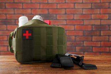 Photo of Military first aid kit and tourniquet on wooden table