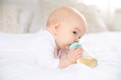 Photo of Pretty baby drinking from bottle on bed at home