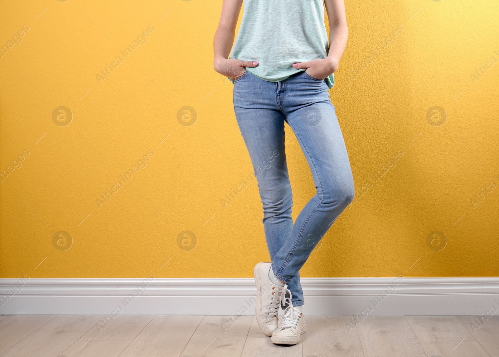 Photo of Young woman in stylish jeans near color wall